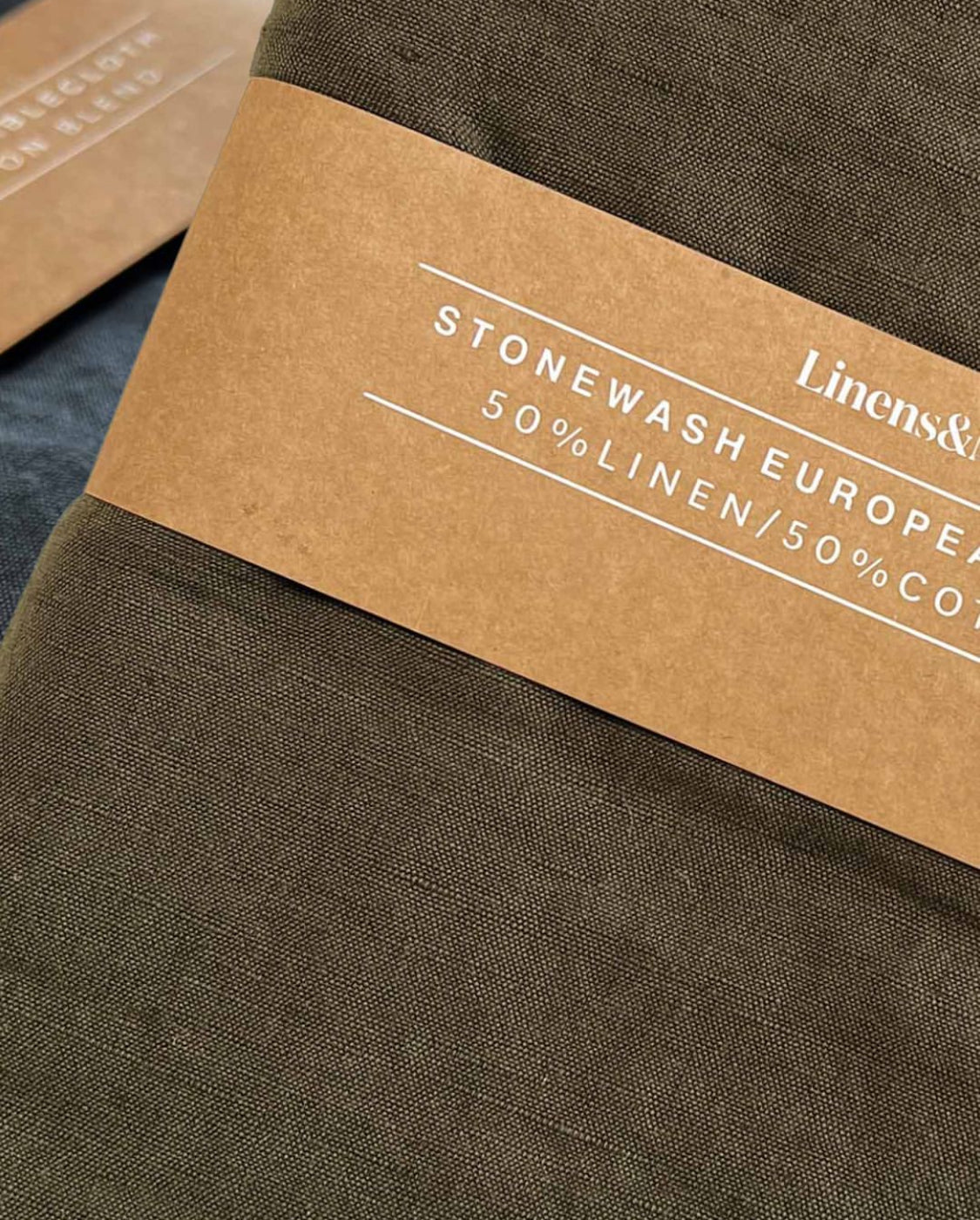 Olive and charcoal tablecloths packaged in a brown belly band with white text.