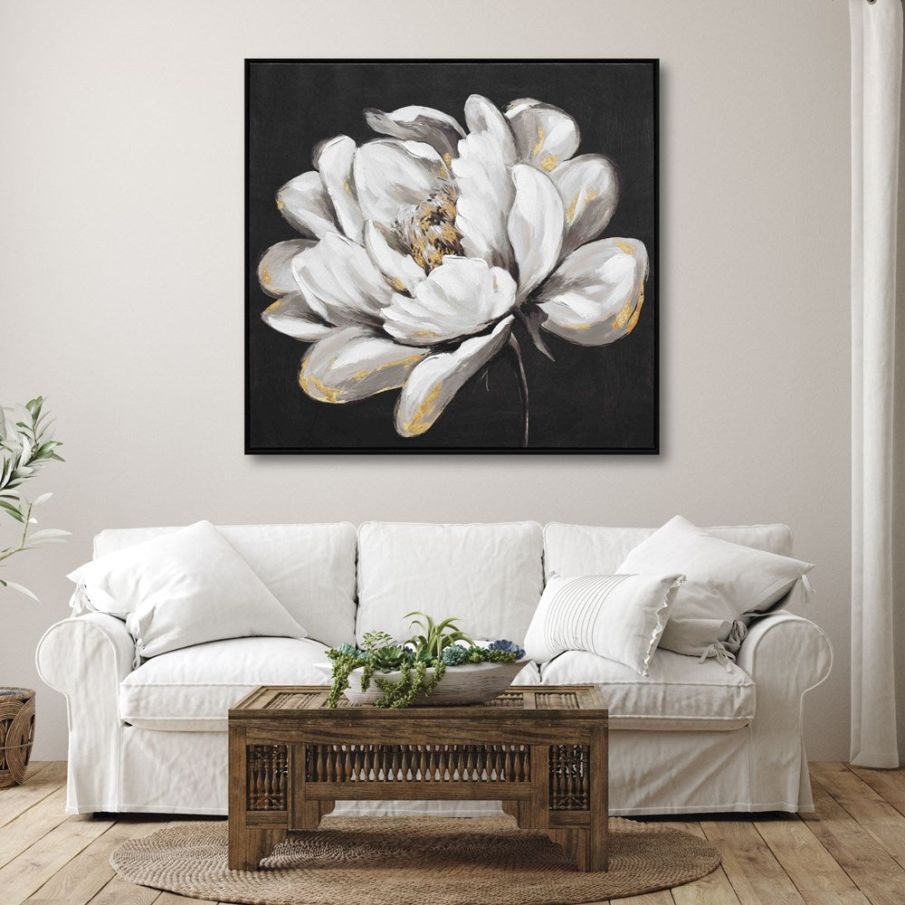 Floral artwork on a wall above a white sofa with a wooden coffee table.