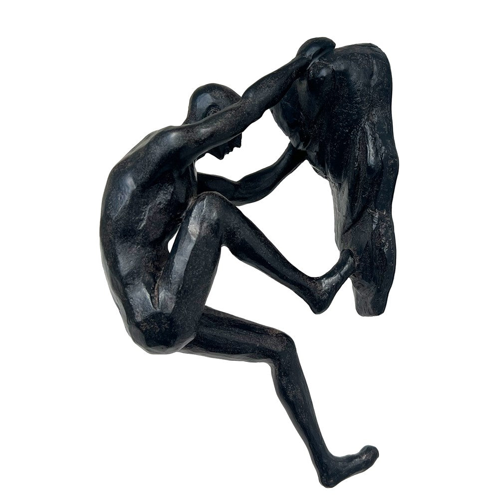 Aged sculpture of a nude figure climbing a rock on a white background