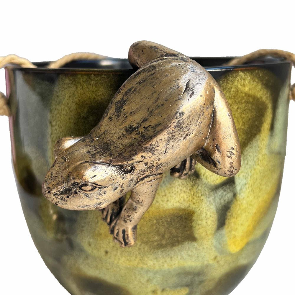 Gold frog hanging off a green planter pot