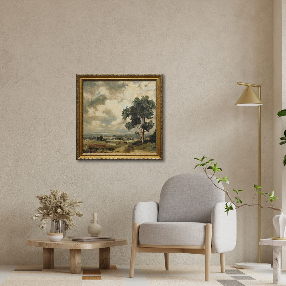 Living room with a gray armchair, wooden side table, and framed landscape painting on the wall.