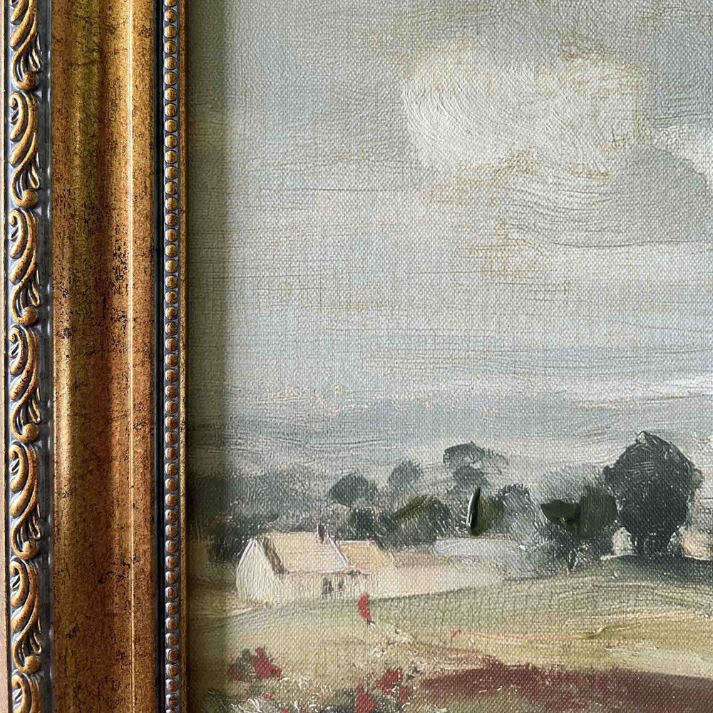 Framed painting of a landscape with houses and trees under a cloudy sky.
