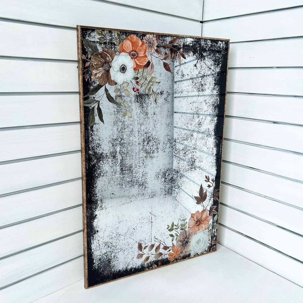 Decorative mirrored wall art with floral design on a white slat background