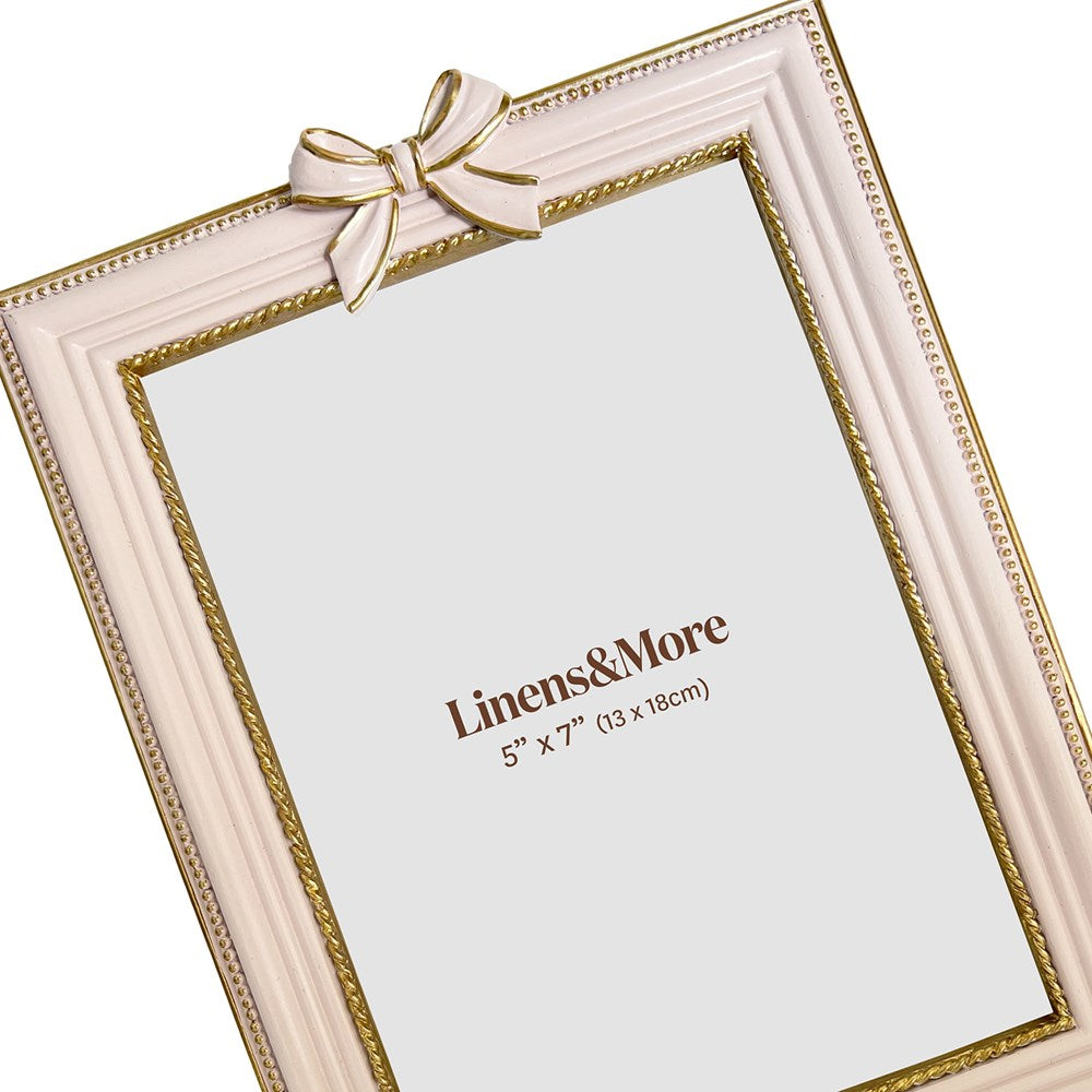 Pink picture frame with a gold bow and 'Linens&More' branding on a white background