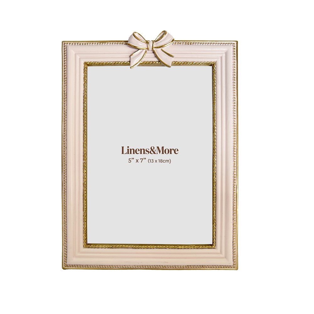 Decorative pink picture frame with a gold bow on a white background.