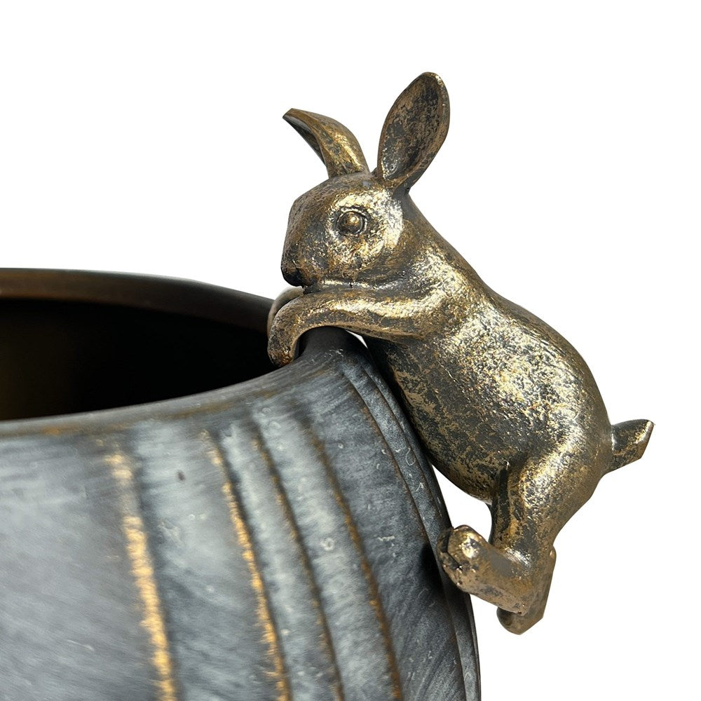 Gold rabbit ornament on a textured pot against a white background