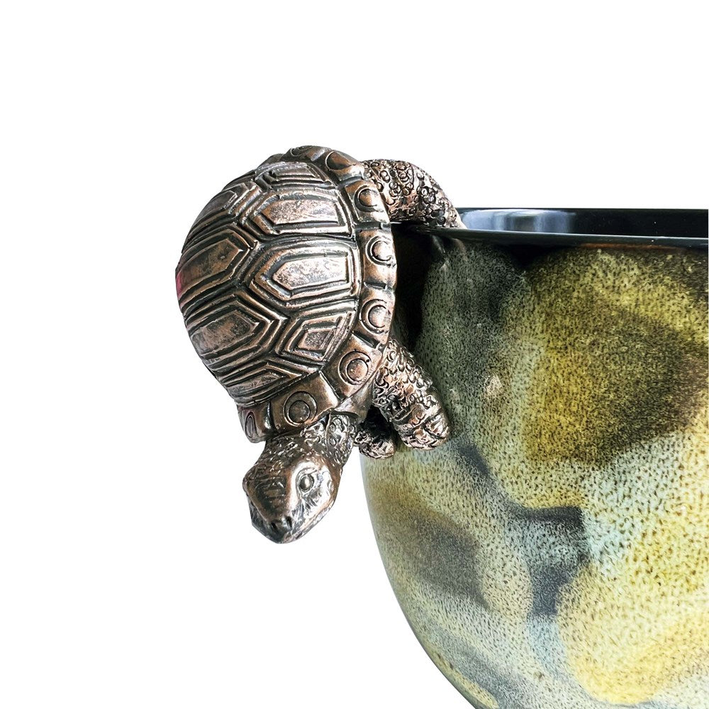 Decorative gold tortoise hanging upside on a pot