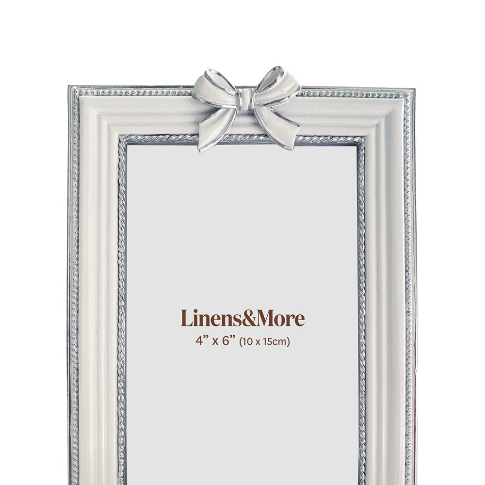 White and silver picture frame with a bow on a white background. 