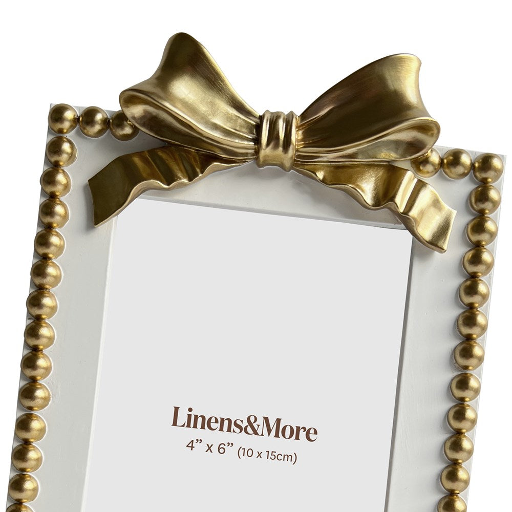 Gold picture frame with bow design and 'Linens & More' branding