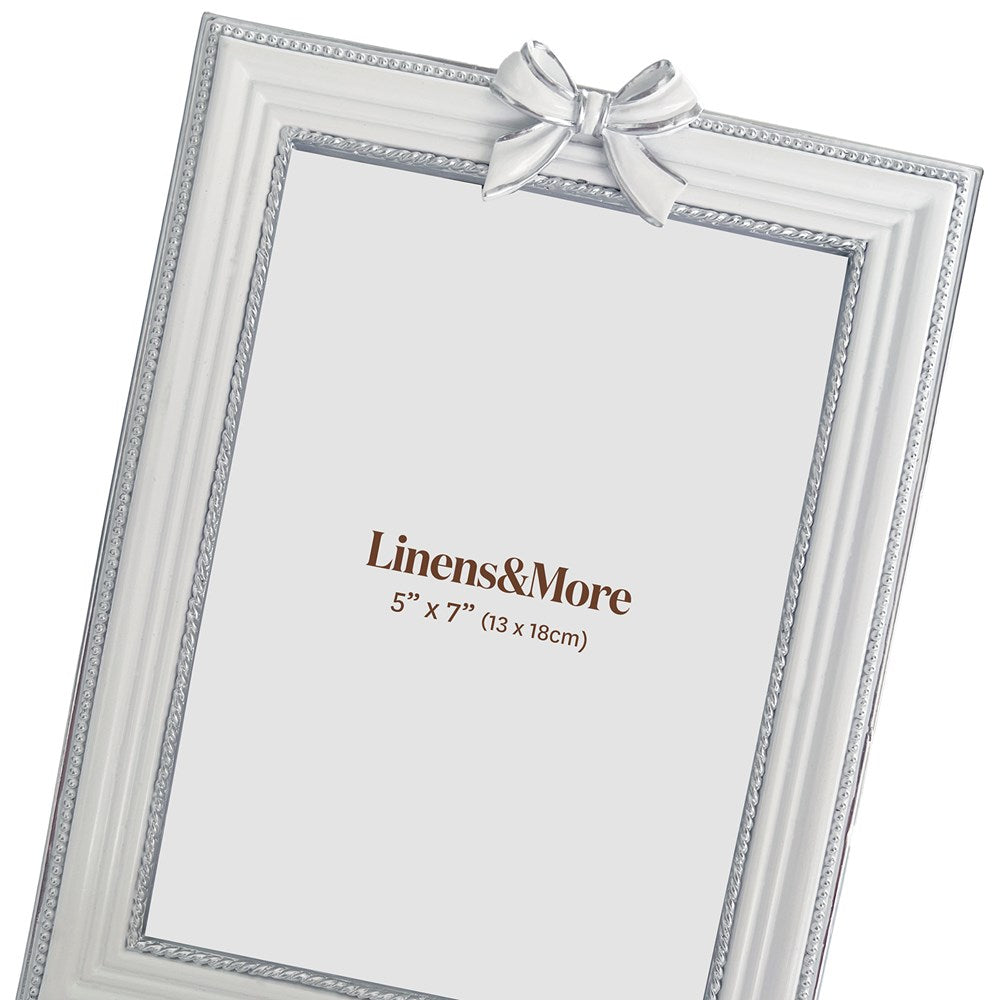 White picture frame with a white bow and 'Linens & More' branding on a white background