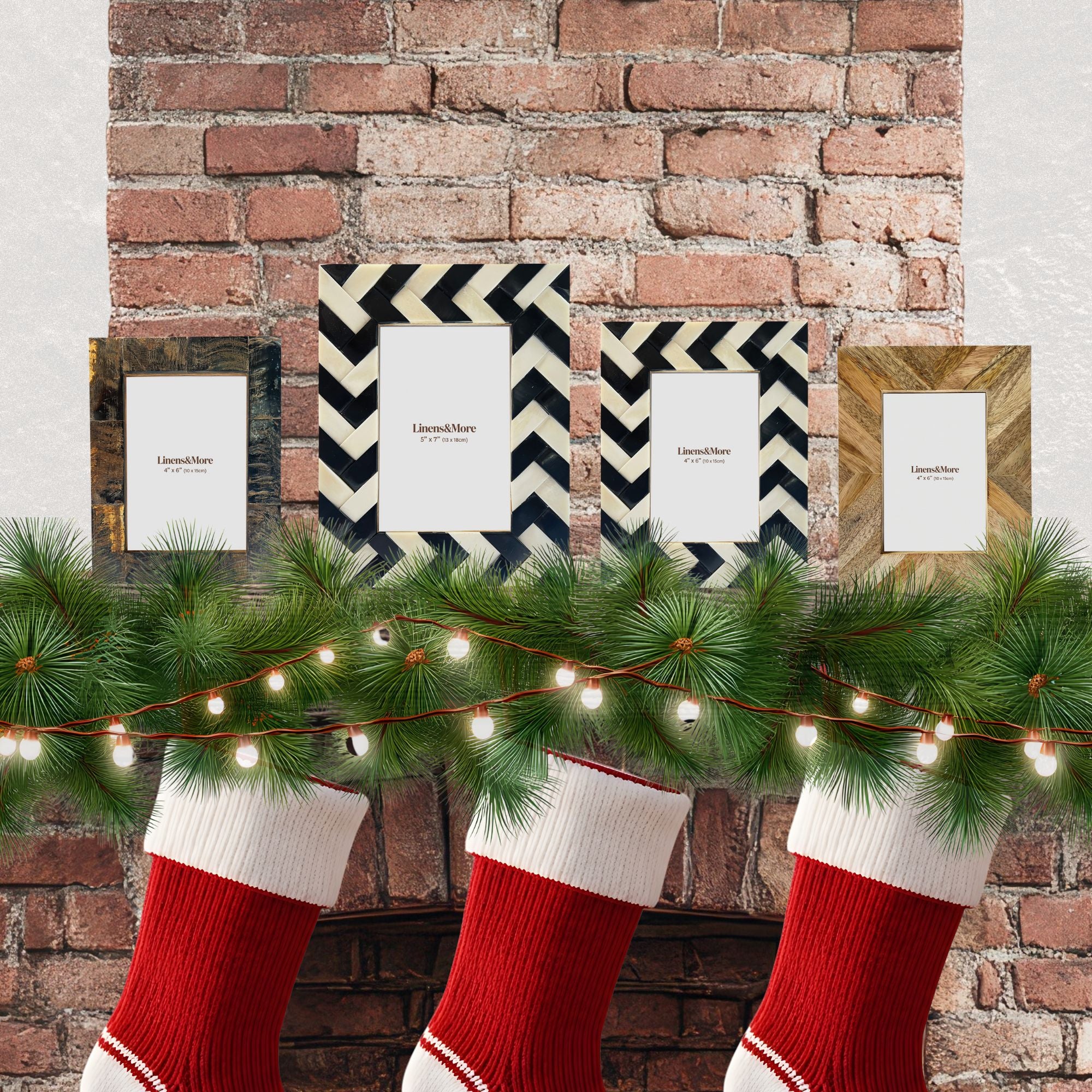 Red Christmas stockings hanging below a mantel with decorative garland and framed pictures against a brick wall.